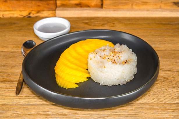 découvrez le délice sucré du riz gluant à la mangue, un dessert populaire thaïlandais alliant la douceur de la mangue mûre à la texture onctueuse du riz gluant, arrosé de lait de coco crémeux. une expérience gustative inoubliable à savourer!